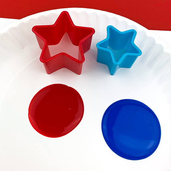 Star cookie cutters in 2 size, red and blue paint placed on paper plate